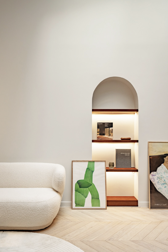 Salon — canapé bouclette, niche arche éclairée, livres, tableau