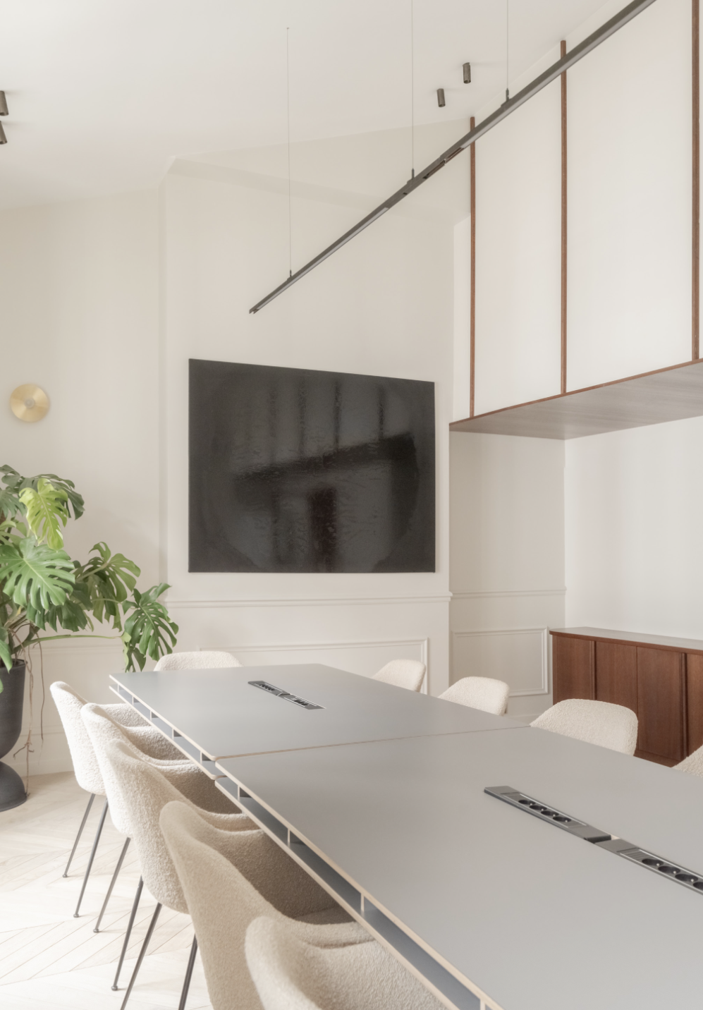 Salle séminaire — table grise, chaises bouclette, écran, monstera